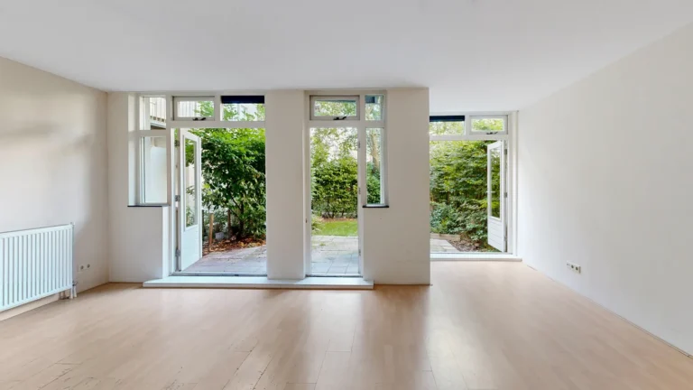 Lege woonkamer met openstaande tuindeuren naar een groene tuin